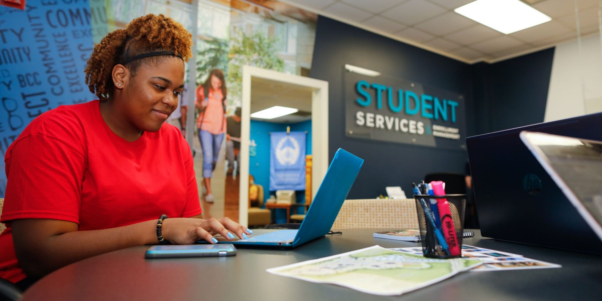 student in red shirt filling out a form on a laptop at BCC