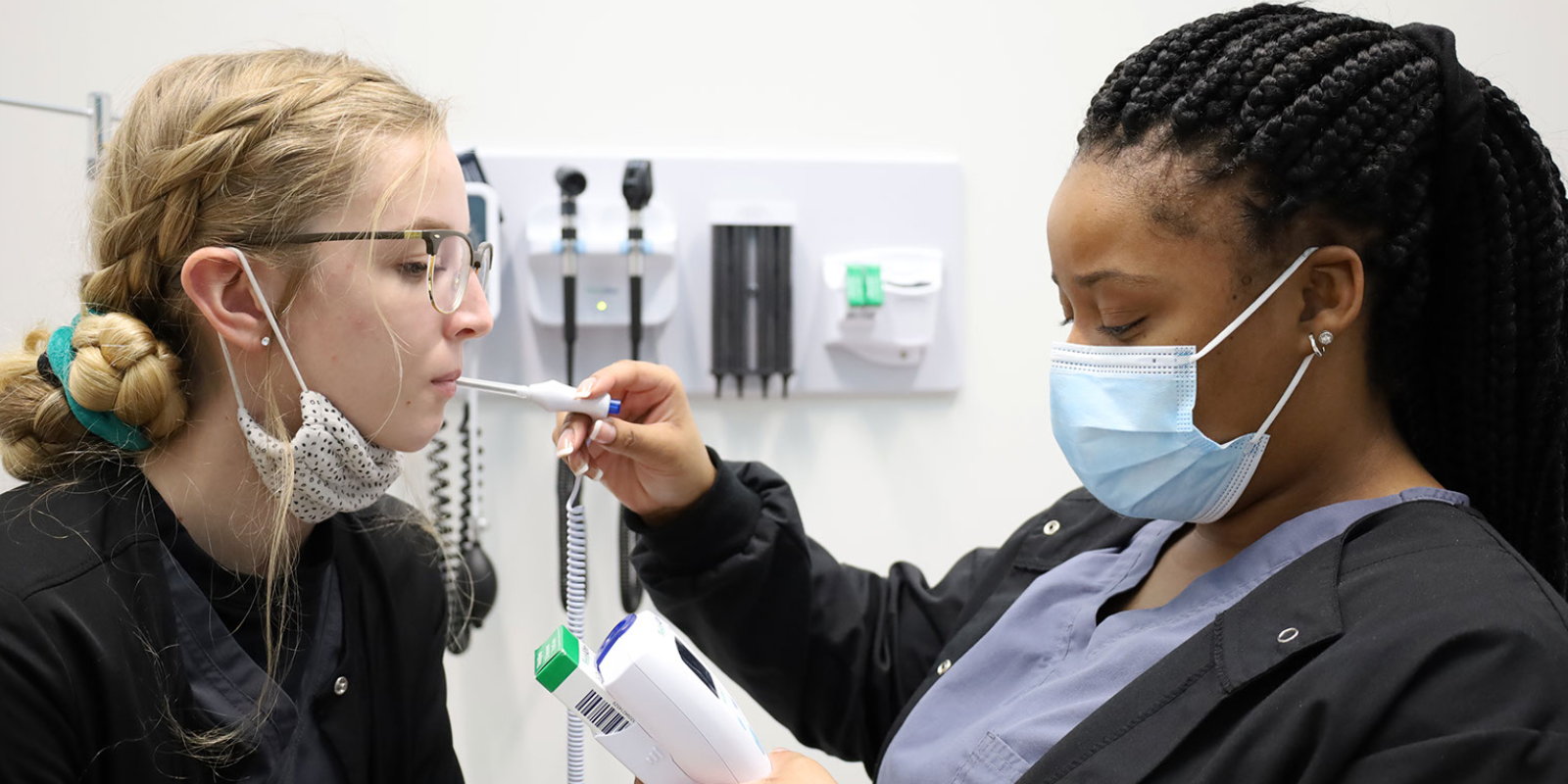 two medical assisting students practicing skills