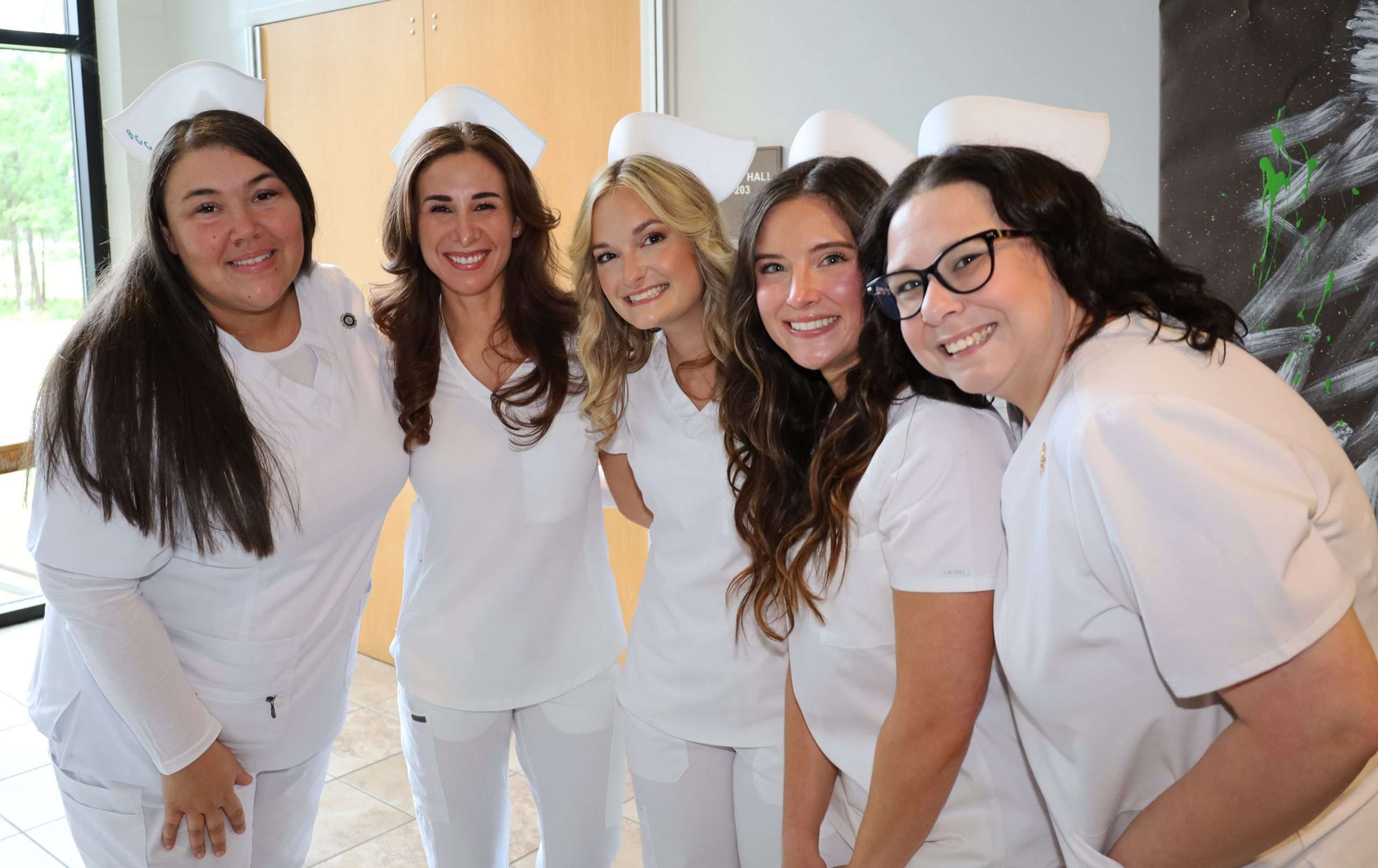 Five nursing graduates smiling in a group shot