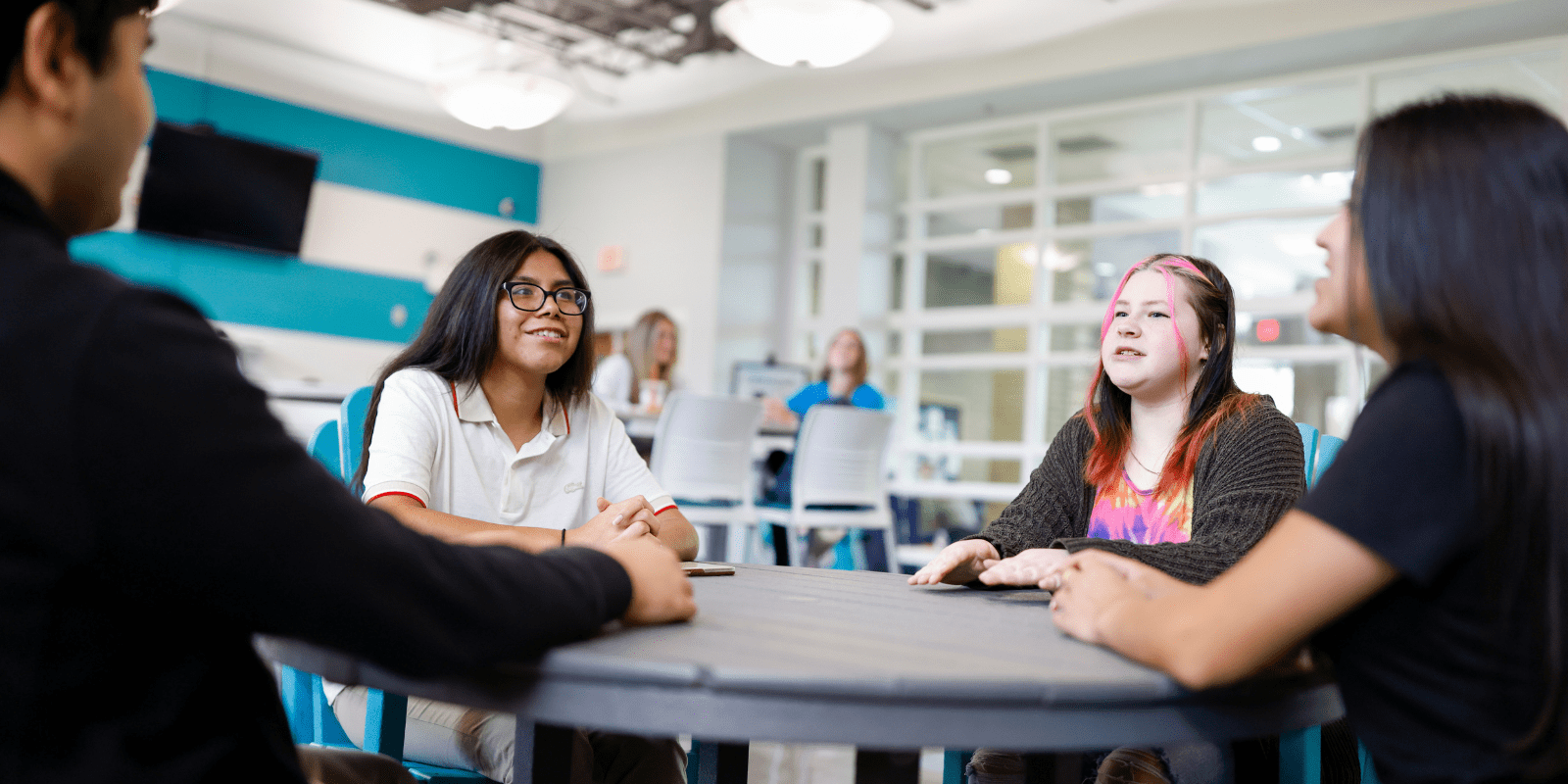 Four BCC students sitting and talking together at a table in Dolphin Cove