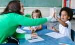 An elementary education teacher giving a student a high five