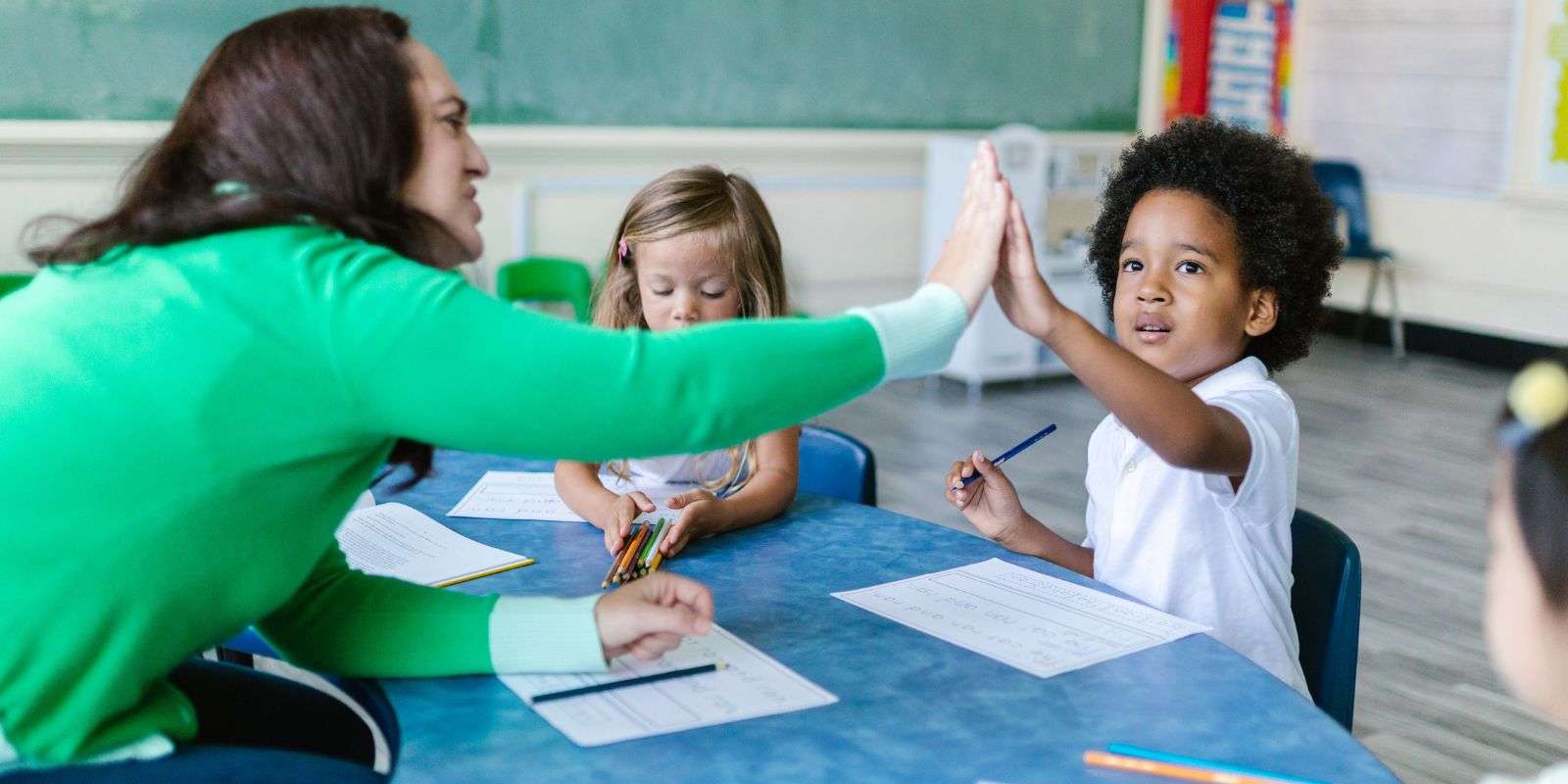 An elementary education teacher giving a student a high five