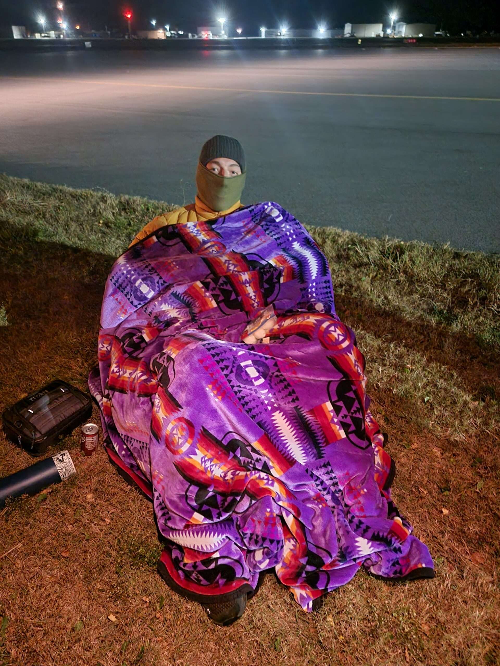 BCC Nursing student wrapped in a blanket and sitting in chair, where he will sleep, at a homeless simulation event.