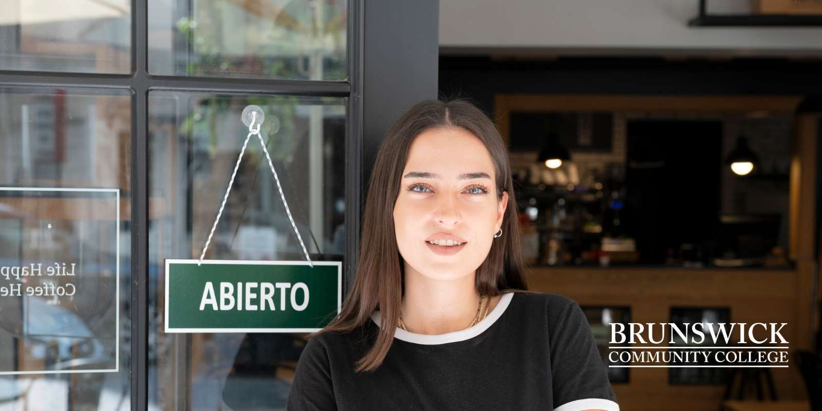 Latina business owner in front of her business with an Open Sign