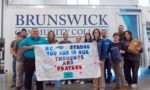 President Smith with the president of Blue Ridge Community College and other employees holding a sign made by BIP after unloading storm relief supplies.