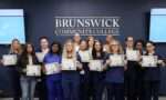 Manicurist program graduates displaying their certificates in a group photo