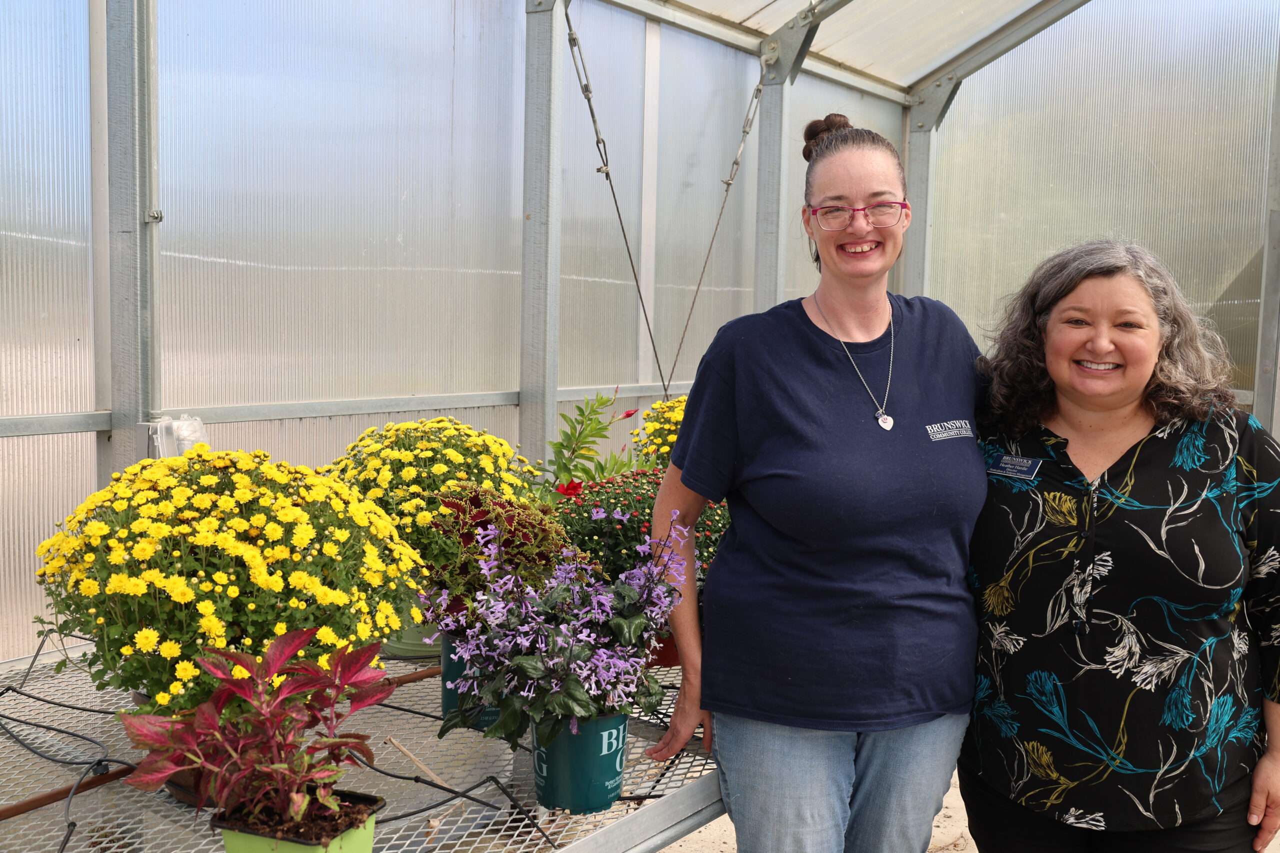 BIP Student Rachael Teeples and Instructor Heather Hardie surrounded by mums in a greenhouse