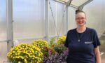 BIP Student Rachael Teeples surrounded by mums in a greenhouse