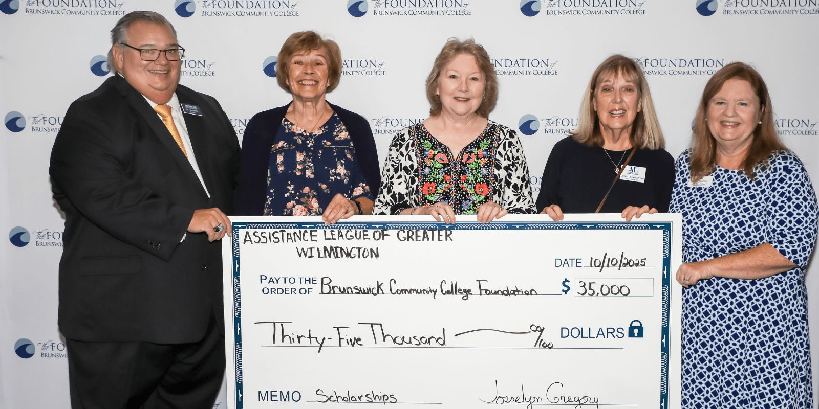 five people holding a donation check and smiling at the camera