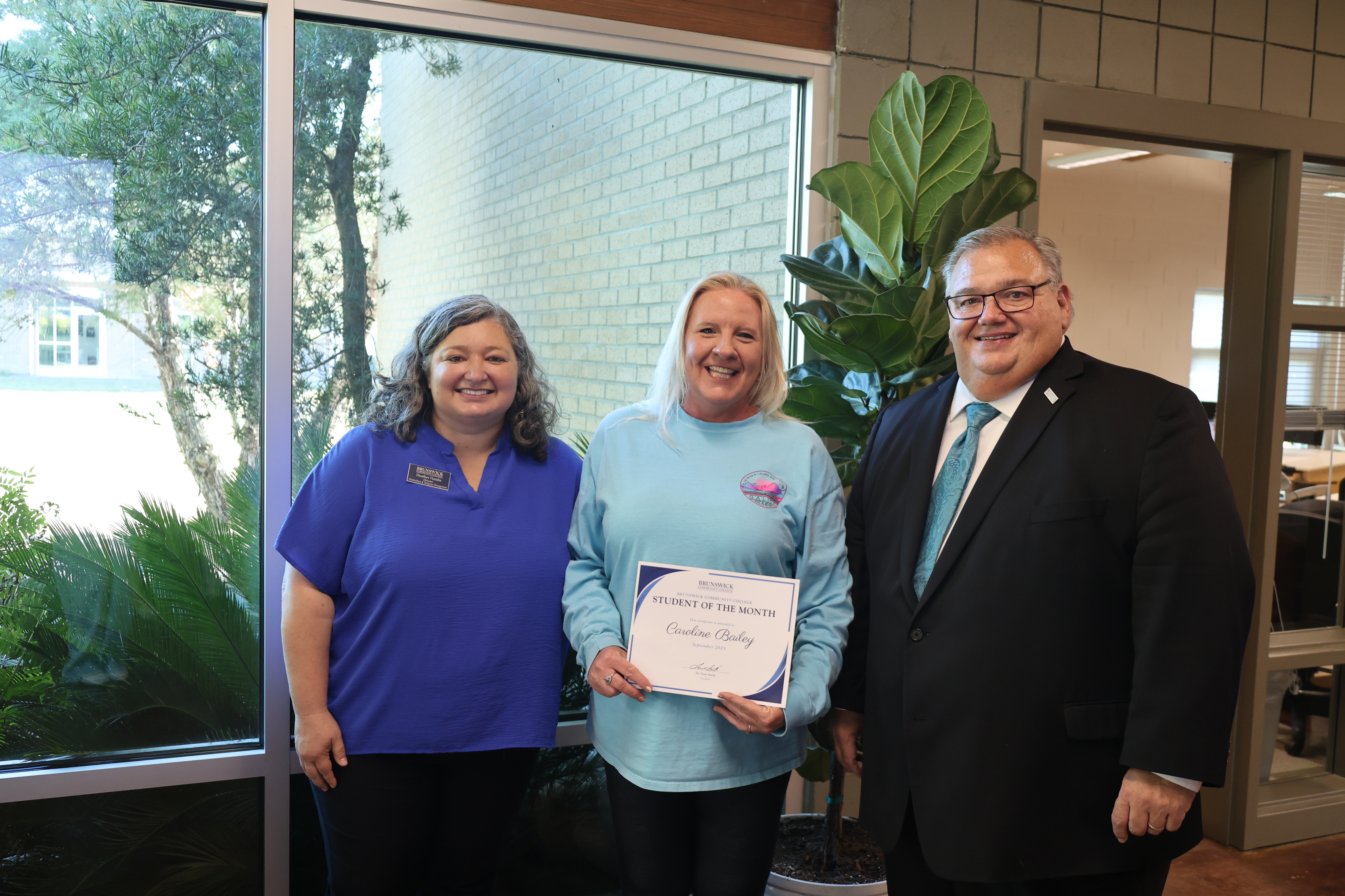 President Smith, Heather Hardie and Student of the Month Caroline Bailey smiling at the camera