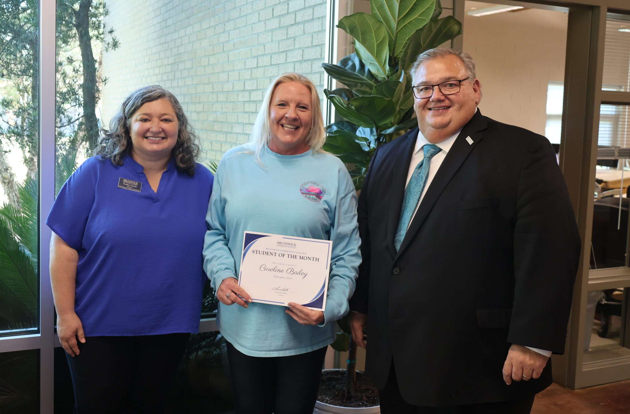 President Smith, Heather Hardie and Student of the Month Caroline Bailey smiling at the camera