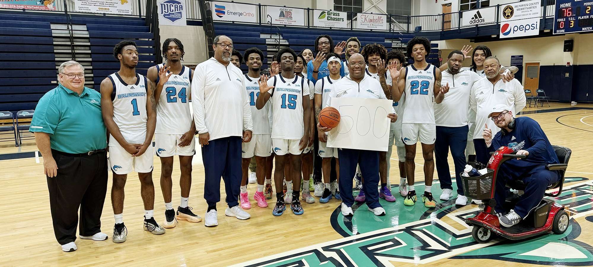 Members of the BCC Men's basketball team surrounding Coach Shaw in celebration of his 500th win