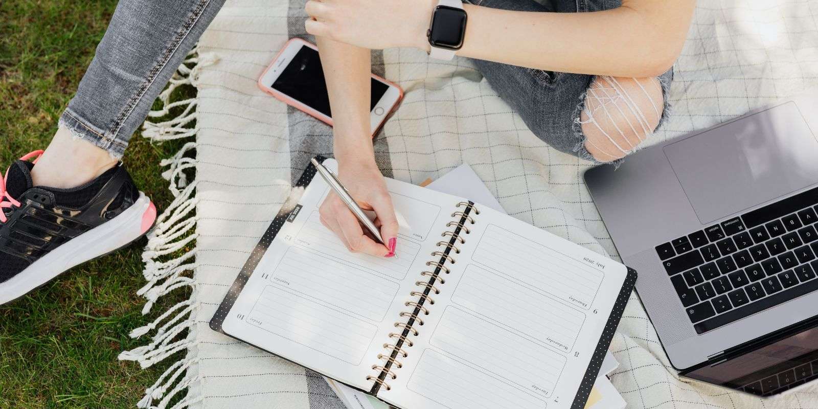 partial image of student with calendar and laptop on grass
