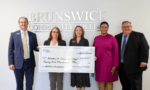 BCC and Duke Energy Foundation representative hold a large check and smile into the camera